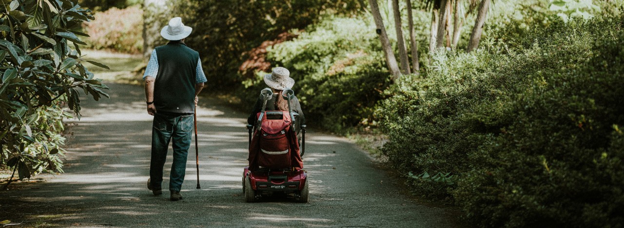 man and woman on path with lightweight mobility scooter