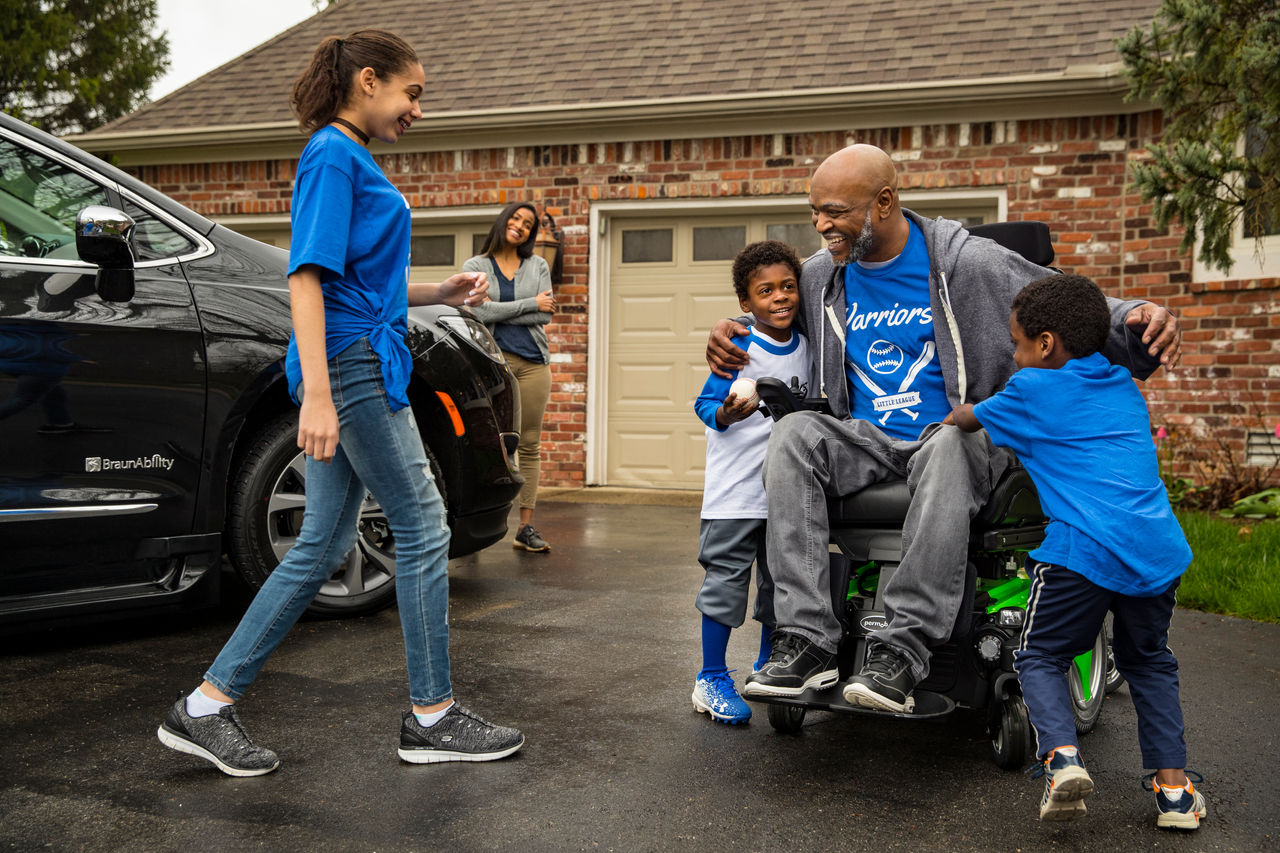 Man in a electric wheelchair huging his kids