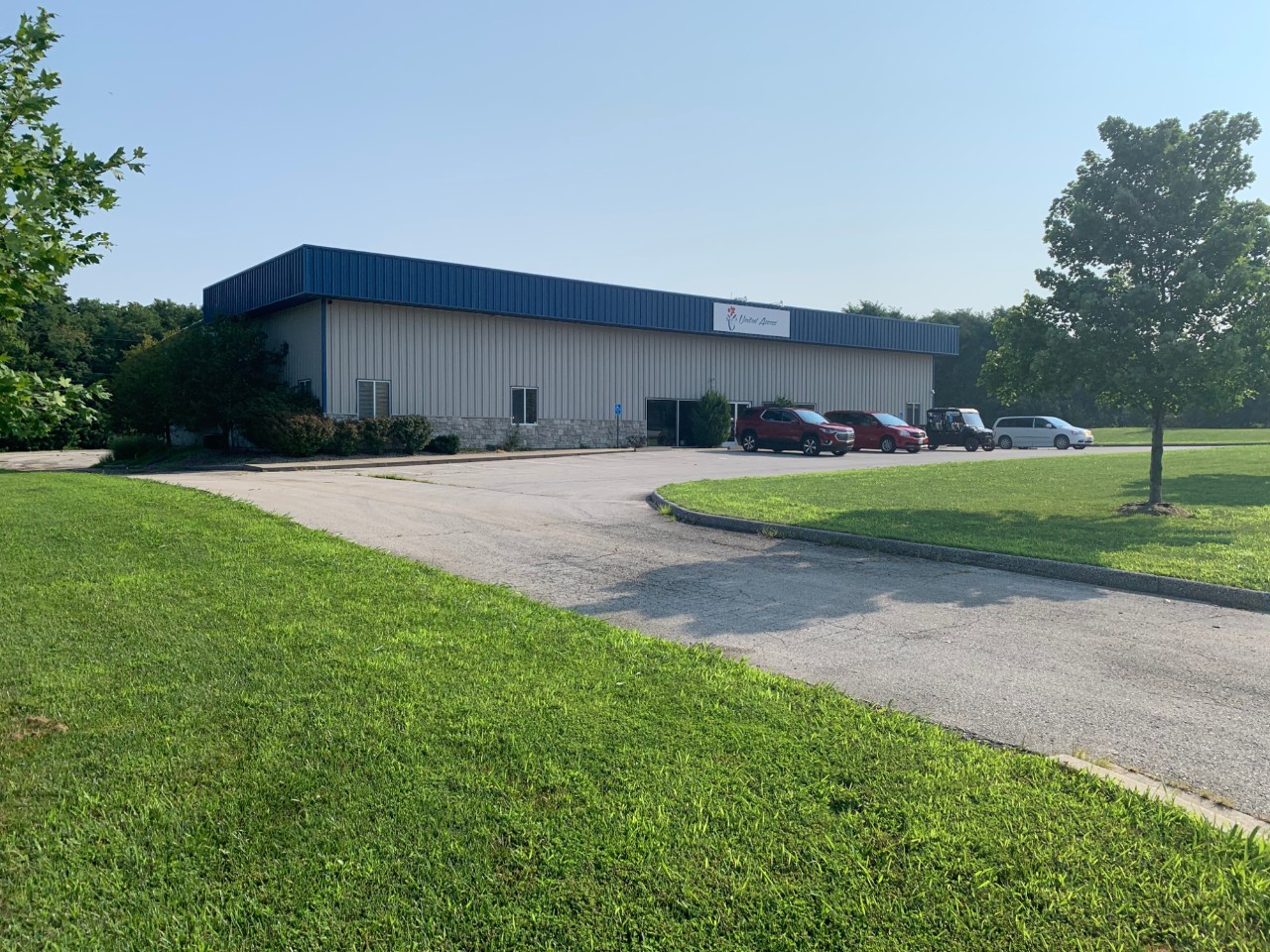 road leading up to entrance of building with dealership in the back